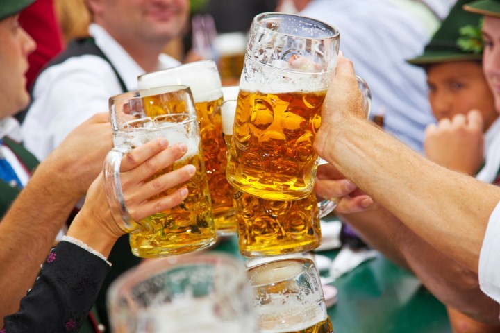 a person holding a glass of beer on a table